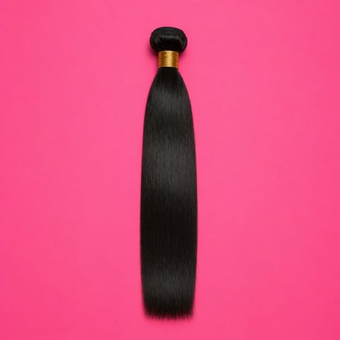 Bundle of long black straight hair extension with gold ferrule against bright pink background