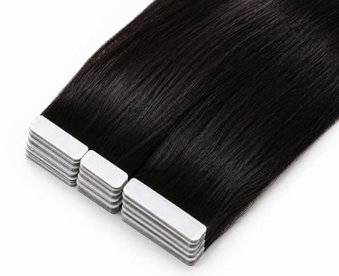 Three strips of black hair extensions with white adhesive tape bases on a white background